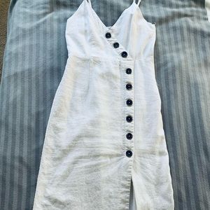 White mid length dress with brown plastic buttons and a zipper on the side